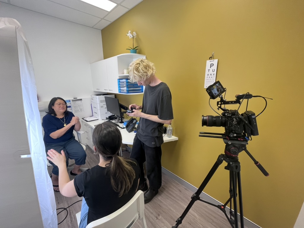 Behind the scenes of a customer-story shoot, with a film crew and camera in a consulting room